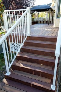 Prestige Woodworks - Christian Neudecker - Deck Builder - 2 Tiered Composite Deck, Double Boarded Fiberon Horizon Line Colour Cinnabar, Main is Fiberon Horizon Line in Colour Ike - Compass is in Fiberon Horizon Line in Colours Tudor Brown and Cinnabar - Border is face screwed and colour matched plugs - Fully Customized Railing System - 4 Custom Staircases - Customized Bench fully Clad in Matching Composite Boarded in Cinnabar to match deck with Covered matching Fascia Boards on Bases