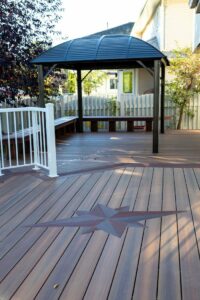 Prestige Woodworks - Christian Neudecker - Deck Builder - 2 Tiered Composite Deck, Double Boarded Fiberon Horizon Line Colour Cinnabar, Main is Fiberon Horizon Line in Colour Ike - Compass is in Fiberon Horizon Line in Colours Tudor Brown and Cinnabar - Border is face screwed and colour matched plugs - Fully Customized Railing System - 4 Custom Staircases - Customized Bench fully Clad in Matching Composite Boarded in Cinnabar to match deck with Covered matching Fascia Boards on Bases